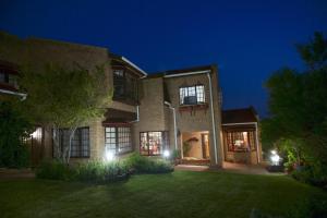 a large brick house at night with lights at Bayside Lodge Garden Route B&B in Plettenberg Bay