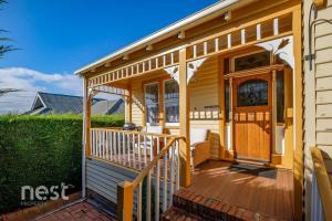 une petite maison avec une terrasse couverte et une terrasse dans l'établissement Belton Apartments-Hedge Cottage, à Hobart