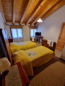 a bedroom with two beds with yellow sheets at Trattoria Albergo all'Alpino in Posina