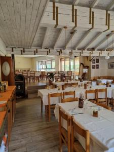 ein Restaurant mit weißen Tischen und Holzstühlen in der Unterkunft Trattoria Albergo all'Alpino in Posina