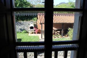 una ventana con vistas al jardín desde una casa en Rodiles Rural Apartamentos en Selorio