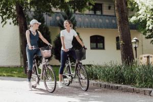 two women riding bikes down a street at Hotel Summerhof in Bad Griesbach