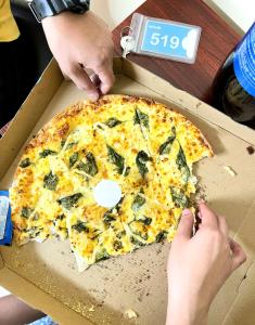 a person is reaching for a pizza in a box at airobedz MAKATI - A Value Hotel in Manila