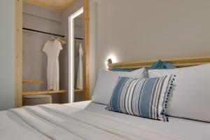 a bed with white pillows and a dress hanging on a closet at Selin Luxury Residences in Ioannina