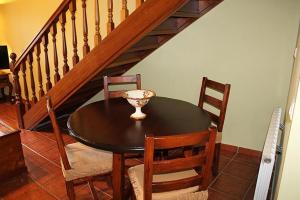 a dining room table and chairs with a staircase at Rodiles Rural Apartamentos in Selorio