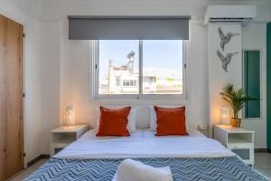 1 dormitorio con 1 cama con almohadas de color naranja y ventana en Sofia's Cosy Studio in Larnaca, en Lárnaca