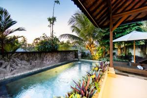 a swimming pool in a resort with palm trees at Villa Natha in Ubud