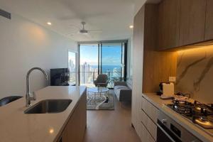 a kitchen with a sink and a view of a living room at Brand new luxury OceanView 2beds apt 40F in Gold Coast