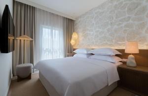 a bedroom with a large white bed and a window at Heritage Hotel Kaštelet in Tučepi