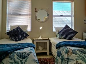 a bedroom with two beds with blue and white pillows at 'The View' on Bikini Beach, Seafront, 2 bedroom, Sleeps 4 in Gordonʼs Bay