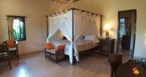 a bedroom with a canopy bed and a chair at Rambutan Hotel in Lovina