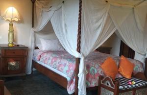 a bedroom with a canopy bed with orange pillows at Rambutan Hotel in Lovina
