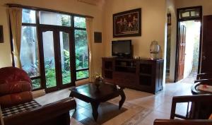 a living room with a couch and a tv at Rambutan Hotel in Lovina