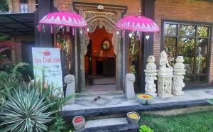 a house with pink umbrellas in front of it at Rambutan Hotel in Lovina