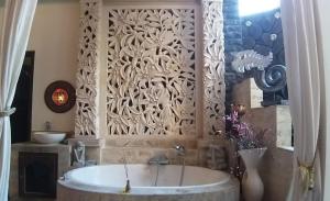 a bathroom with a tub and a wall with a window at Rambutan Hotel in Lovina