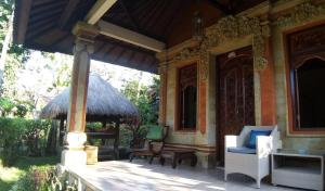 a porch of a house with a chair and a bench at Rambutan Hotel in Lovina