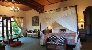 a bedroom with a large bed with a canopy at Rambutan Hotel in Lovina