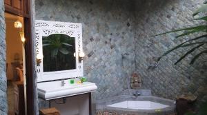 a bathroom with a sink and a bath tub at Rambutan Hotel in Lovina