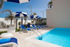 uma piscina com guarda-sóis e cadeiras azuis e brancos e uma piscina em Hotel Nautilus em Cagliari