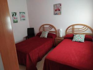 2 camas en una habitación con sábanas rojas en Jesús Del Perdón, en Manzanares