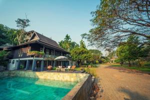 una casa con piscina frente a ella en Baan Suan Residence เฮือนพักบ้านสวน, en Chiang Mai