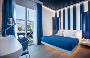 a blue and white bedroom with a bed and a desk at Hotel Nautilus in Cagliari