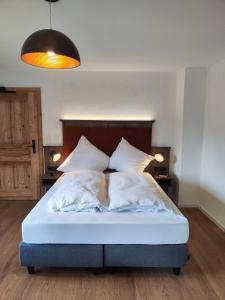 uma cama com lençóis brancos e almofadas num quarto em Chiemseehof em Prien am Chiemsee