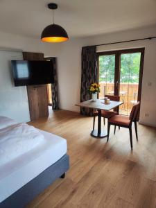 a bedroom with a bed and a table and a tv at Chiemseehof in Prien am Chiemsee