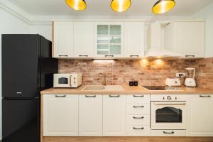 a kitchen with white cabinets and a black refrigerator at Amfora Maris Apartment in Split
