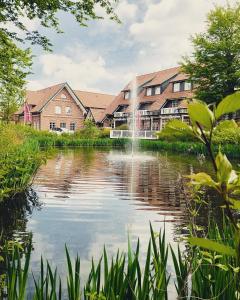 einem Teich vor einem Gebäude mit einem Brunnen in der Unterkunft Schützenhof Ahlerstedt in Ahlerstedt