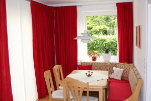 a dining room with red curtains and a table at Das Blaue Haus - Ferienwohnung Schönherr in Kassel