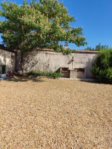 un muro di pietra con un albero in un cortile di Ardèche les cigales, studio laurier a Grospierres