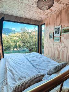 un letto in una camera con una grande finestra di Elysian Fields - The Island Tiny House a Sadu