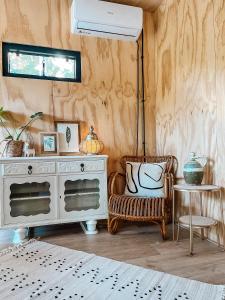 Habitación con cómoda blanca y silla en Elysian Fields - The Island Tiny House, en Sadu