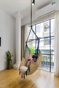 a swinging hammock in a room with a large window at Leaf Signature Hotel - Lá Group in Ho Chi Minh City