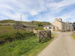 a house on a dirt road next to a fence at Cwm Ceiliog Annex in Caernarfon