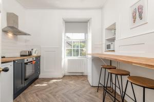 a kitchen with white walls and a counter with stools at The Doctor's House Central with Street Parking in St. Andrews