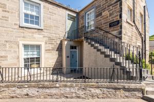 a brick building with stairs and a blue door at The Doctor's House Central with Street Parking in St. Andrews