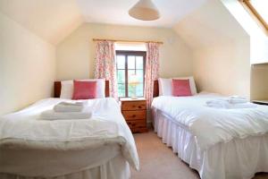 two beds in a room with a window at Garbity Cottage in Fochabers