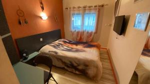 um quarto com uma cama, uma secretária e uma janela em Hôtel Le Bambi em Baume-les-Dames