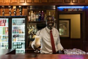 a man in a tie standing behind a bar at Tzaneen Country Lodge in Tzaneen