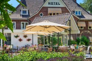 a restaurant with an umbrella in front of a building at Hotel 't Kruisselt in De Lutte