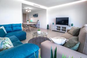 ein Wohnzimmer mit blauen Sofas und einem Flachbild-TV in der Unterkunft Emerald Green 2380 Golf & beach in San Roque