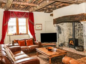 a living room with leather furniture and a stone fireplace at Yr Hen Dy in Colwyn Bay