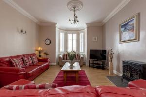 sala de estar con sofás rojos y TV en The Knowe, en Portpatrick
