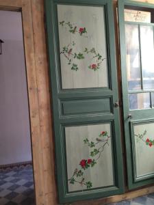une paire de portes avec des fleurs peintes sur elles dans l'établissement chambres d'hôtes Le Carillon, à Bergues