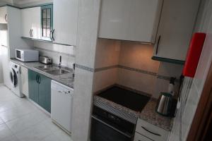 Elle comprend une petite cuisine avec des placards blancs et un évier. dans l'établissement Urban Beach - Apartamento Pôr do Sol, à Portimão