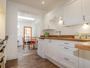 cocina con armarios blancos y suelo de madera en Pen-Y-Thon House en Newquay