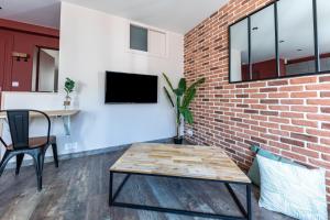 uma sala de estar com uma parede de tijolos e uma mesa em NOUVEAU - T2 Industriel - Quartier historique - WiFi - Parking - Netflix em Hennebont