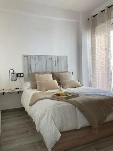 Dormitorio blanco con cama grande y cabecero de madera en Coqueto apartamento de Playa con Piscina y Terraza, en Valencia